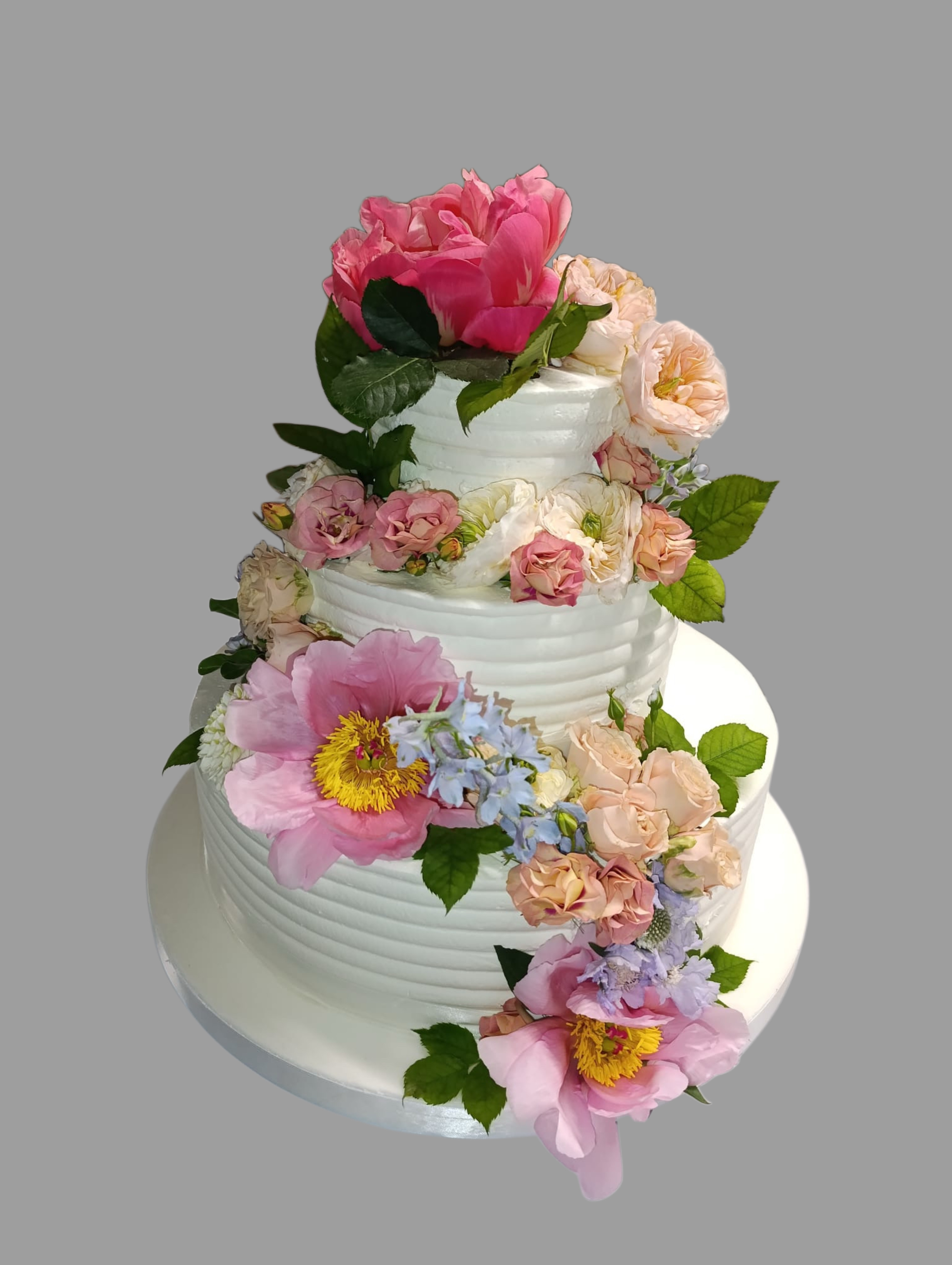 Torta matrimoniale bianca a tre piani con una cascata di fiori rosa e foglie verdi